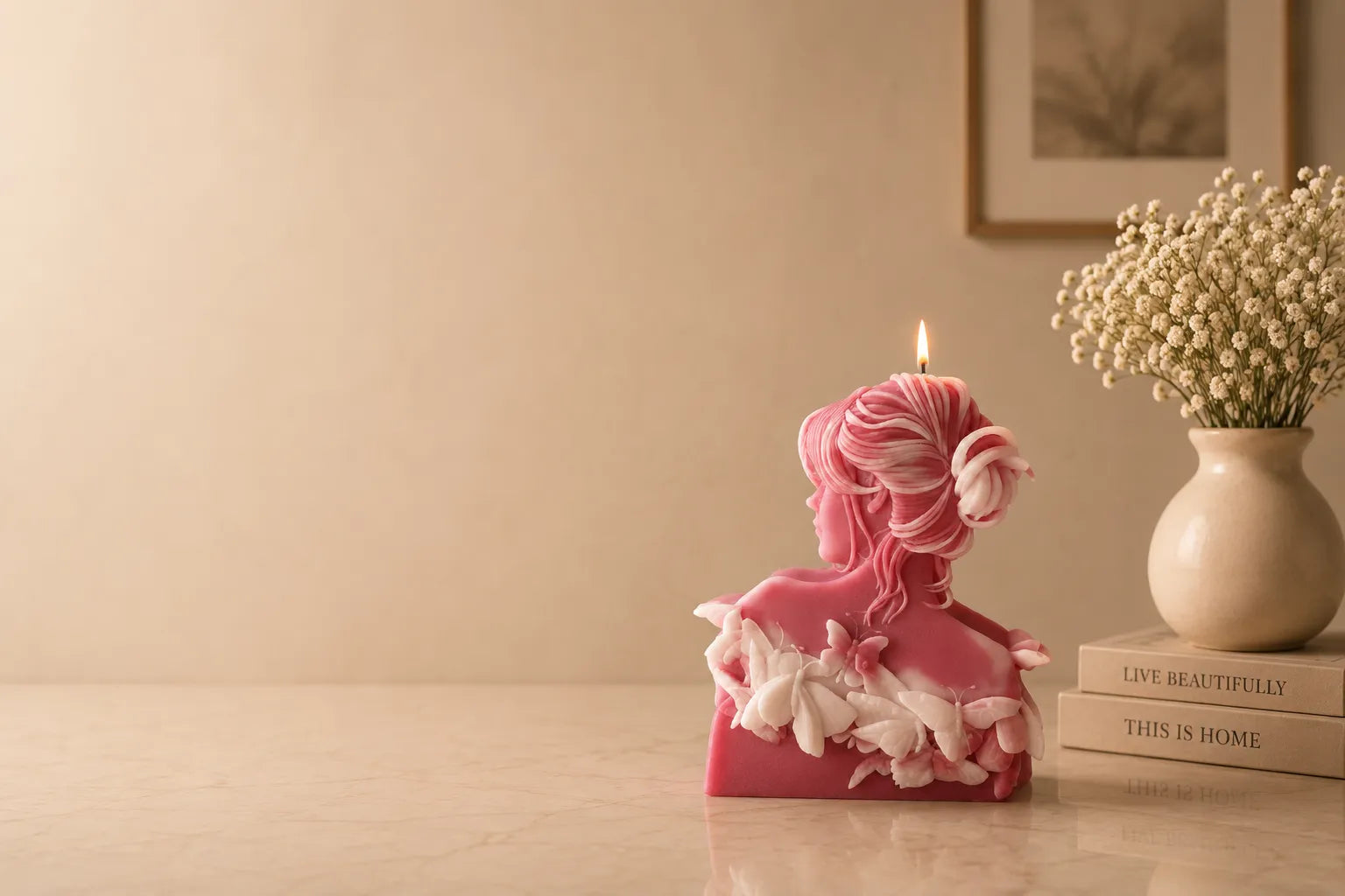Pink candle shaped like a woman with flowers on a wooden surface.