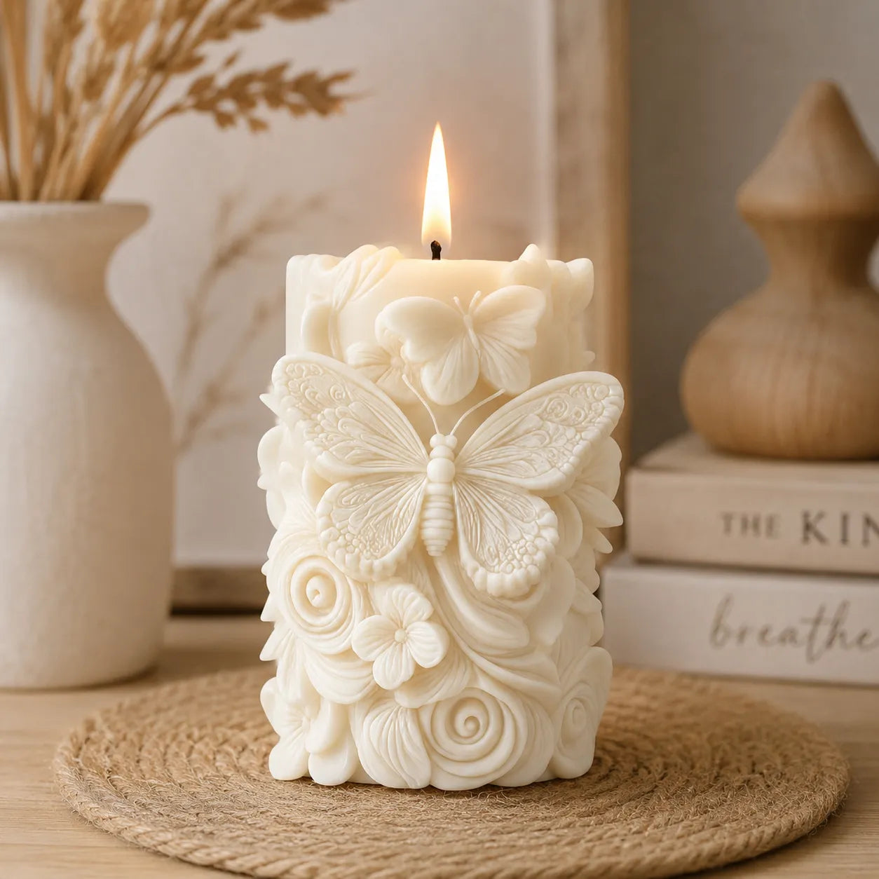 Decorative candle with butterfly and floral design on a woven mat