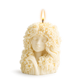 Candle shaped like a woman's face with floral hair on a white background