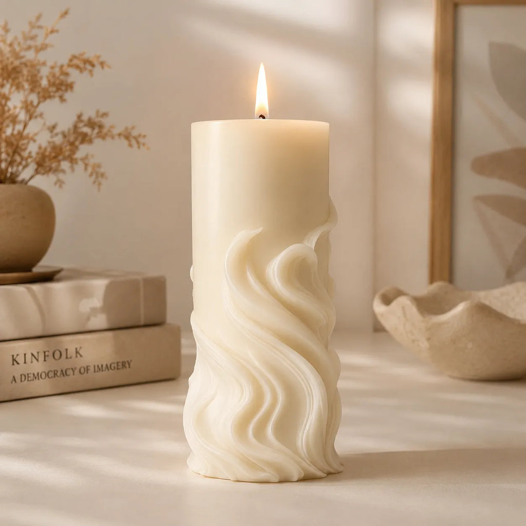 White wavy-textured candle burning on a surface with books and decor in the background
