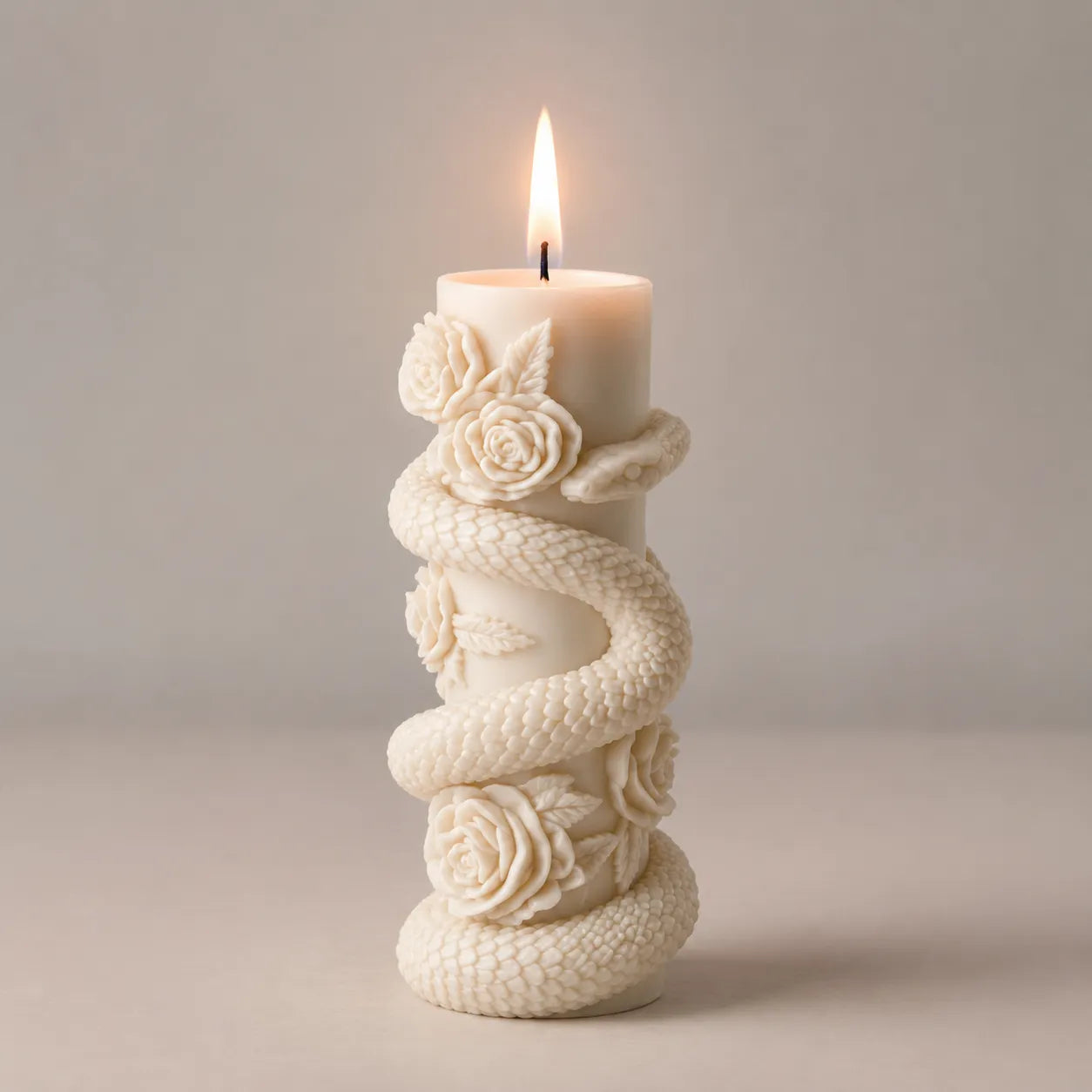 Decorative candle holder with floral designs and a lit candle on a neutral background