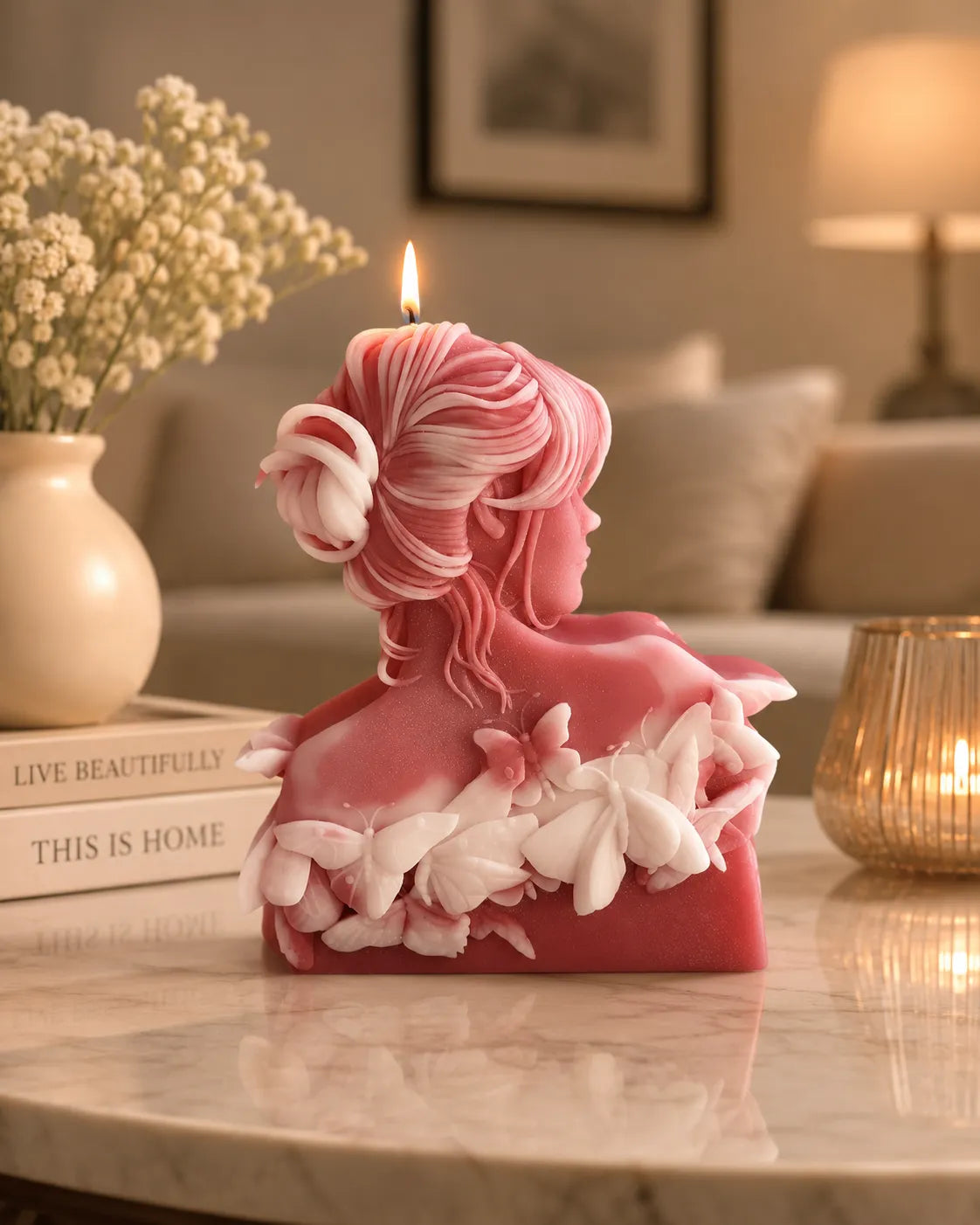 Pink and white decorative candle shaped like a woman's bust on a marble surface.