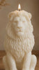 Decorative lion sculpture candle burning softly on a wooden surface with a warm neutral background.